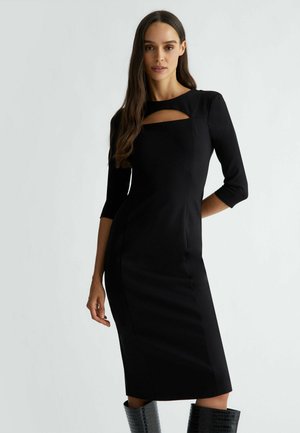 Vestito nero aderente con maniche a tre quarti, scollatura quadrata con dettaglio a taglio e texture liscia.