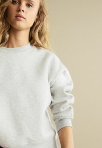 Hellgrauer Sweatshirt mit Rundhalsausschnitt, gerippten Bündchen und lässiger Passform aus weichem, strukturiertem Stoff.