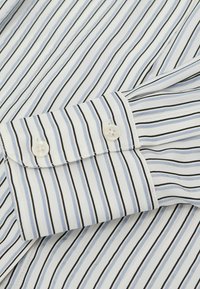 Helehall-valge triibuline särk mustade joontega, millel on nööbitav mansett ja sile kangapind.