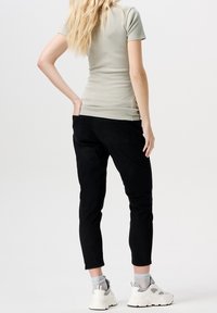 Tajt ljusgrå topp med korta ärmar, i kombination med svarta smala jeans och vita sneakers, som visar en strukturerad tygkvalitet och avslappnad stil.