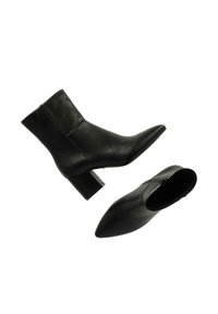 Botas de tobillo de cuero negro con un acabado texturizado, punta afilada y tacón grueso. Cuentan con un cierre de cremallera en el lado.