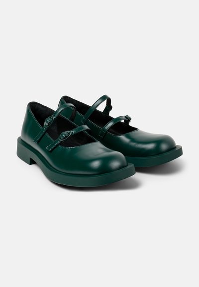 Green leather shoes with two adjustable straps, rounded toe, flat sole, and a smooth finish. Designed for comfort and stability.