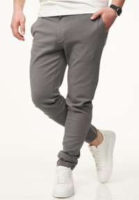 Gray jogger pants with a tapered design, elastic waistband, and cuffed ankles. Paired with white sneakers, showcasing a casual look.