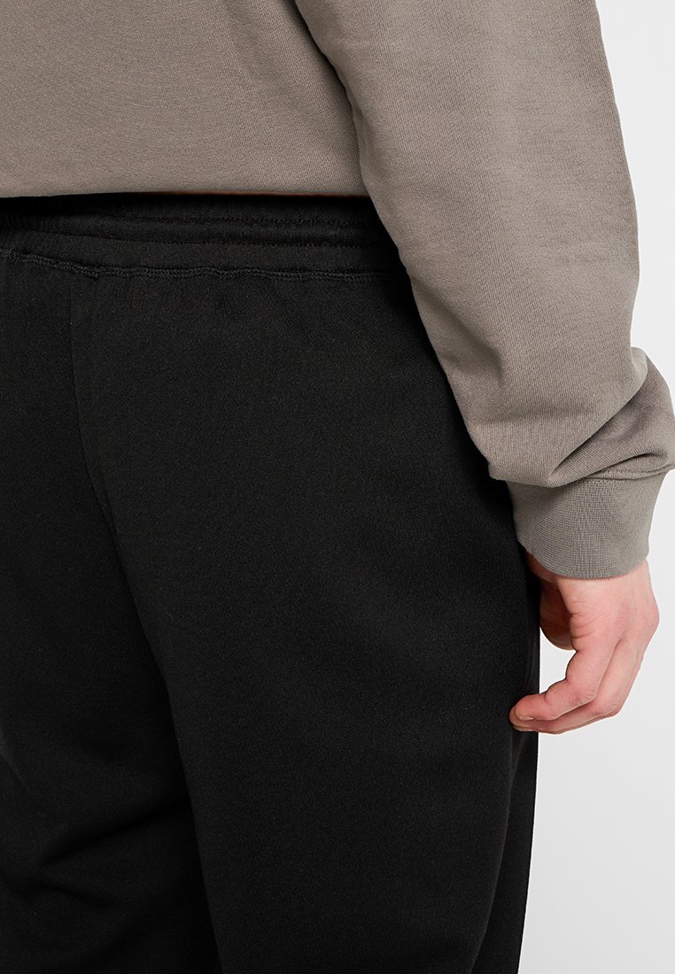 Svarta joggerbyxor med en mjuk textur och elastisk midja, tillsammans med en ljusgrå sweatshirt med långa ärmar.