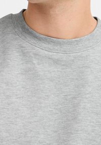 Sudadera gris con un cuello acanalado, textura suave y un diseño simple y limpio. Detalle de costura visible alrededor del cuello.