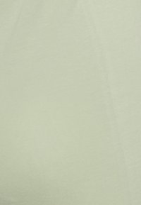 Tecido de algodão verde-claro e suave com uma textura lisa, apresentando um leve brilho e costuras mínimas visíveis ao longo das bordas.