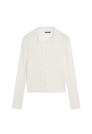 Cardigan blanc à côtes avec des manches longues, un col et une fermeture à boutons sur le devant, présentant une finition texturée subtile.