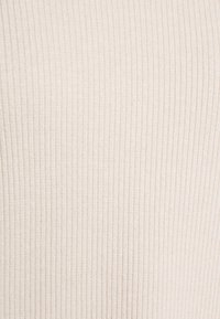 Beiger, gerippter Stoff mit feinen vertikalen Streifen, der eine weiche Textur und ein konsistentes Muster über das Material hinweg zeigt.