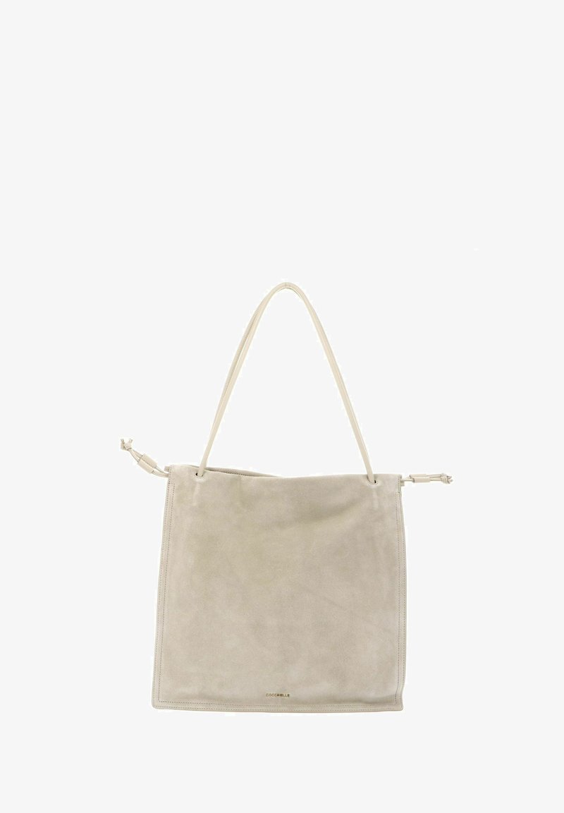 Borsa tote in suede beige con sottile tracolla e dettagli annodati ai lati, cuciture minimaliste e piccolo logo dorato vicino al centro in basso.