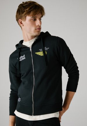 Black zip-up hoodie with hood, featuring yellow graphic and logo on the chest, ribbed cuffs, and hem, made from a soft cotton blend fabric.