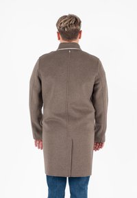 Cappotto in lana marrone con colletto a stand-up, piega sul retro e maniche lunghe. Il tessuto ha una consistenza liscia e una vestibilità su misura.