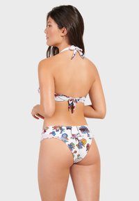 Bikini set med halterneck, vit bas och färgglada mönster. Bikiniunderdel med vågig kant och en tight passform.