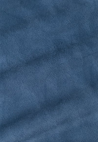 Material in suede blu con una superficie morbida e testurizzata. Il tessuto appare stropicciato e soffice, riflettendo delicatamente la luce sulla sua superficie.