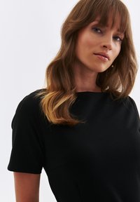 Black short-sleeve dress with a high neckline and smooth texture, featuring subtle seam details and a fitted silhouette.