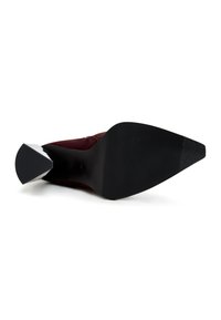 Scarpa con tacco alto color bordeaux, con punta affusolata e suola in gomma nera texturizzata. Il tacco presenta un accento metallico argento.