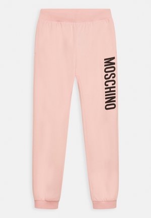 Jasnoróżowe spodnie dresowe z elastyczną talią i ściągaczami, z pogrubionym czarnym napisem "MOSCHINO" nadrukowanym pionowo na prawej nodze.