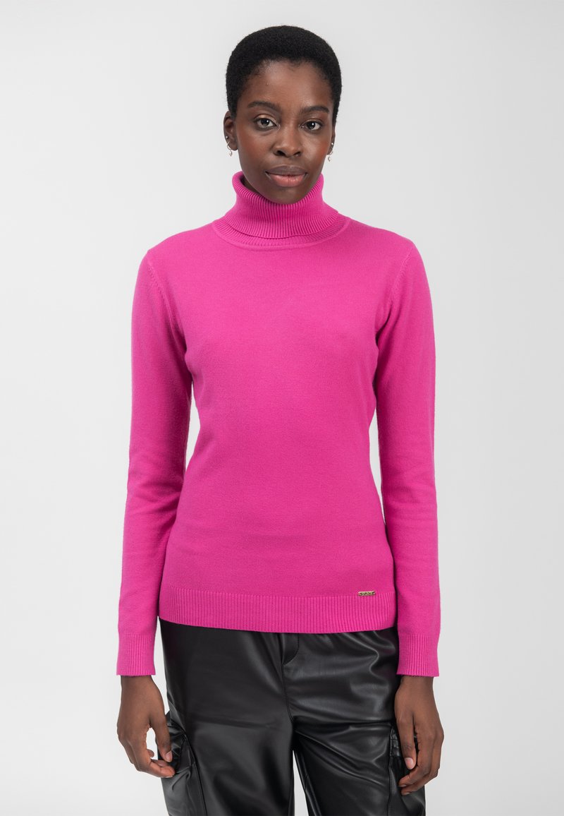 Fuchsia Rollkragenpullover aus weichem Strickstoff, mit gerippten Bündchen und Saum. Ein kleines metallisches Logo-Detail befindet sich am unteren Ende.
