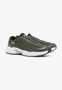 Scarpe da atletica verdi realizzate in materiali mesh e sintetici, con una superficie texturizzata, suola intermedia bianca, design con lacci e dettaglio del logo.