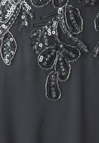 Mustkunst mustriga mustri ja hõbedaste aktsentidega beadwork'iga must kangas, mis lisab tekstuuri ja detaile.