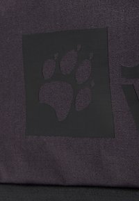 Silhouette di impronta di zampa nera su tessuto viola scuro texture, con una finitura liscia. Il design include un contorno quadrato attorno all'impronta di zampa.