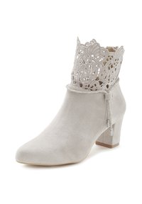 Botín de ante gris hasta el tobillo con un borde de encaje en forma de ondas, ribete plateado y un tacón cuadrado, que presenta un detalle decorativo de borlas.