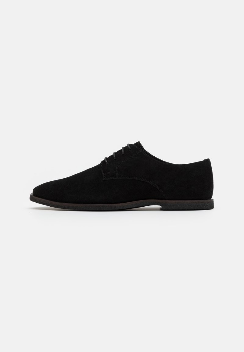 Chaussure habillée à lacets pour homme en daim noir, avec un talon bas et une semelle lisse, vue de profil sur fond blanc.