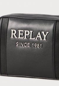 Borsa in pelle sintetica nera con logo "REPLAY" in rilievo e "SINCE 1981" in argento. Texture liscia con dettagli a contrasto.