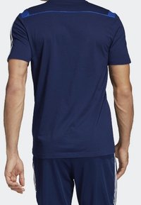 Camiseta deportiva de color azul marino con mangas cortas, que presenta acentos azules en los hombros y un cuello redondo. Tejido suave, corte casual, sin logotipos visibles.