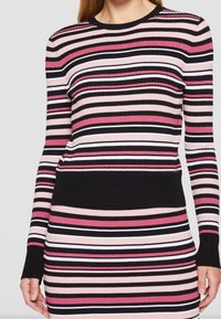 Pull en tricot ribbé avec des rayures horizontales rose, noir et blanc. Encolure ras du cou classique, manches longues et taille contrastante en noir.