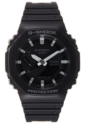 Svart G-Shock klokke med rund urskive, digital og analog visning, grå detaljer og en teksturert gummirem. Vanntett ned til 20 bar.