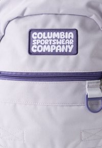 Ανοιχτό μωβ σακίδιο με υφασμάτινο εξωτερικό, που διαθέτει θήκη με φερμουάρ και ορθογώνιο μωβ κεντητό λογότυπο για την Columbia Sportswear Company.