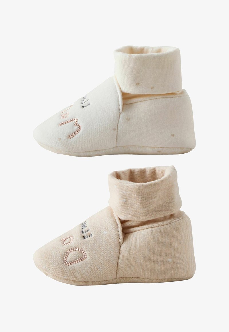 Two soft baby booties in light cream and beige colors with ankle cuffs and embroidered text on the top sides.