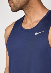 Dunkelblaues Nike-Tanktop mit rundem Ausschnitt, hergestellt aus strukturiertem Stoff, mit kleinem silbernem Swoosh-Logo oben links.