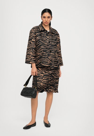 Zwart en bruin met tijgerstrepen oversized jasje en rok set, gecombineerd met een gewatteerde zwarte handtas en zwarte ballerina's. Soepele stoftextuur.
