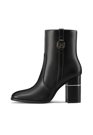 Stivale alla caviglia in pelle nera con punta appuntita, tacco largo e dettagli in metallo dorato vicino alla caviglia. Texture liscia.