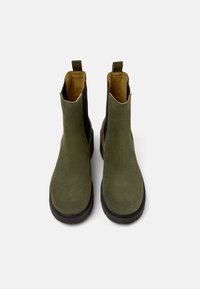 Stivali alla caviglia verde in suede con pannelli laterali neri, punta rotonda e suola in gomma testurizzata. Presenta due linguette per una facile calzata.