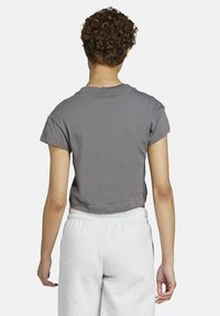 Grijze cropped t-shirt met korte mouwen, voorzien van een getailleerd ontwerp en zachte textuur, gecombineerd met lichtgrijze joggers.