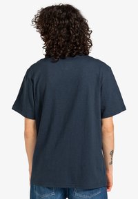 Granatowa koszulka z krótkim rękawem o luźnym kroju, z okrągłym dekoltem i miękką teksturą. Widok z tyłu pokazuje minimalne detale.