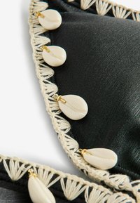 Czarny materiał o gładkiej fakturze, obszyty kremowobiałym warkoczem i ozdobiony dekoracyjnymi muszlami. Wyróżniają się złote akcenty metalowe.