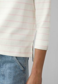 Lichtgewicht, crème katoen top met roze horizontale strepen, driekwart mouwen, zijsplitten, gecombineerd met een blauwe denim rok.