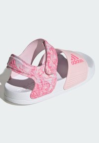 Chanclas rosas con un diseño de tira veteada y una tira rosa sólida. Suela blanca con acentos texturizados y detalle del logo. Cierre de velcro.
