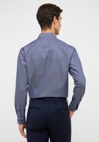 Langarmhemd in Navyblau mit weißen vertikalen Streifen, ausgestattet mit einem Button-Down-Kragen und kontrastierenden Knöpfen an den Manschetten und am Rücken.