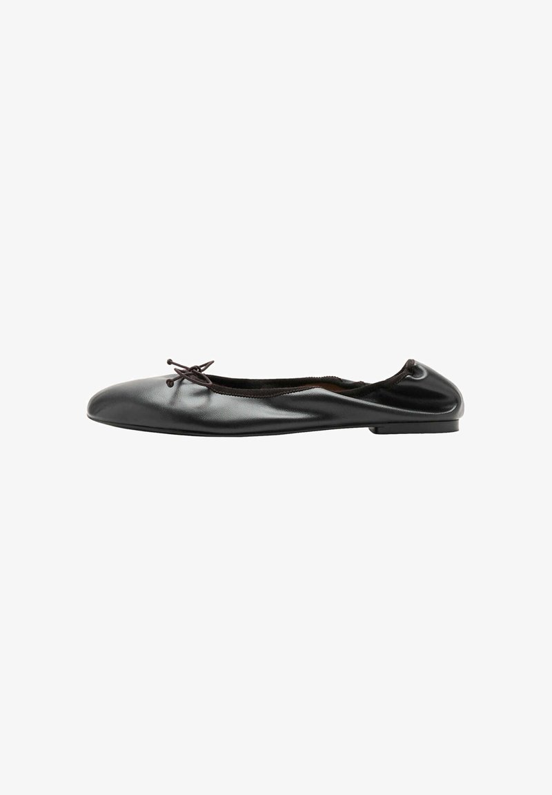 Ballerine en cuir noir avec un petit nœud à l'avant et une couture arrière légèrement froncée, vue de profil sur fond blanc.