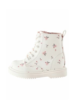 Botte blanche pour tout-petit avec motif floral rose, lacets à l'avant et semelle en caoutchouc, vue de côté.