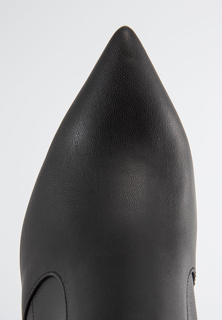 Schwarze spitz zulaufende Lederschuhe mit glatter Oberfläche, von oben betrachtet vor weißem Hintergrund.