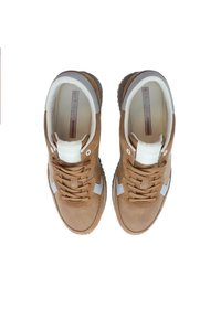 Bruna mockaskor med vita detaljer, rund tå, snörning framtill, vadderad krage och gummisula. Vy ovanifrån.