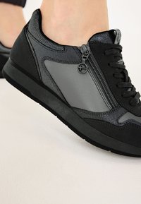Sneaker neri e grigi caratterizzati da un mix di pelle e tessuto, con chiusura a zip e dettagli testurizzati sui lati. Suola in gomma piatta.