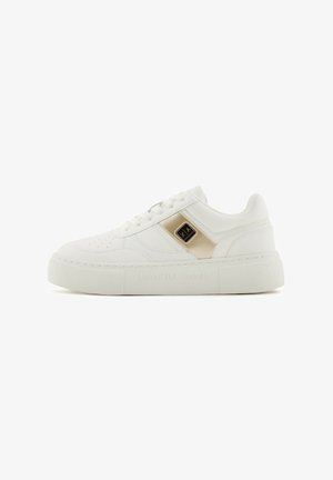 Baskets blanches en simili cuir avec une texture lisse, semelle plate, accents dorés et détails perforés au niveau des orteils.