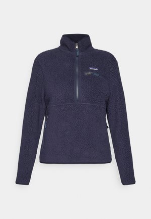 Marineblauwe fleecejas met hoge kraag, halve ritssluiting aan de voorkant, ritszak op de borst en het Patagonia-logo op de linkerkant van de borst.