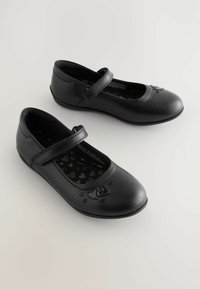 Chaussures Mary Jane en cuir noir avec un bout rond, une bride sur le cou-de-pied et des semelles intérieures à motif en forme de cœur. Texture lisse et design minimaliste.